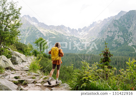 Smiling traveler with a bright backpack on a hiking mountain trail. Active lifestyle. Smiling traveler with a bright backpack on a hiking mountain trail. Active lifestyle. 131422916