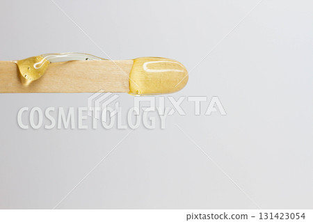 The inscription cosmetology on a wooden spatula with wax for hair removal. The inscription cosmetology on a wooden spatula with wax for hair removal. 131423054