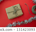 Packing Christmas gifts. Gift, twine and tinsel on a red background. 131423093