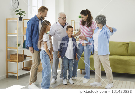 Big happy family congratulates son and grandson standing at home in living room. Big happy family congratulates son and grandson standing at home in living room. 131423828