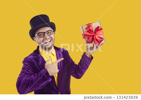 Portrait of happy man in hat and purple suit pointing at Christmas present and smiling Portrait of happy man in hat and purple suit pointing at Christmas present and smiling 131423839