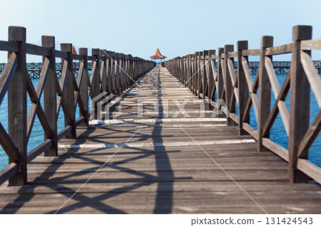 Long wooden pier with traditional gazebos - bale stretches over calm turquoise sea under clear blue sky. Perfect place for viewing amazing landscape.  Scenery for travel, resort, summer vacation 131424543