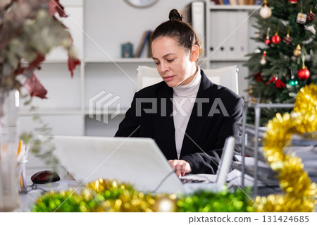 Woman working in workplace in Christmas decorated office Woman working in workplace in Christmas decorated office 131424685