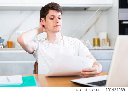 Young guy studying at home with laptop Young guy studying at home with laptop 131424689