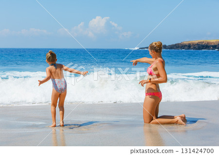 Mother, daughter playing together on beach, enjoying waves and warm summer day. Family vacation fun by ocean with kids. White sand, turquoise sea. Travel lifestyle, summer holiday, beach destinations Mother, daughter playing together on beach, enjoying waves and warm summer day. Family vacation fun by ocean with kids. White sand, turquoise sea. Travel lifestyle, summer holiday, beach destinations 131424700