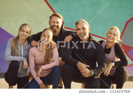Happy young sport group of people jumping standing in a circle with hands up in nature. 131425769