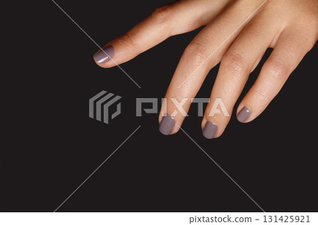 Closeup of female hand with short nails and fashion grey manicure in coffee shade on dark backdrop. Professional Nail art perfect for Beauty Salon, Nail Artist, Cosmetic Store concepts 131425921