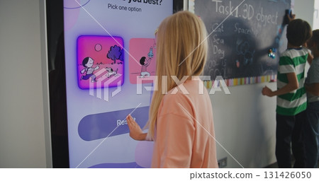 Young Blonde Schoolgirl in Classroom Takes Temperament Test on Digital Screen 131426050