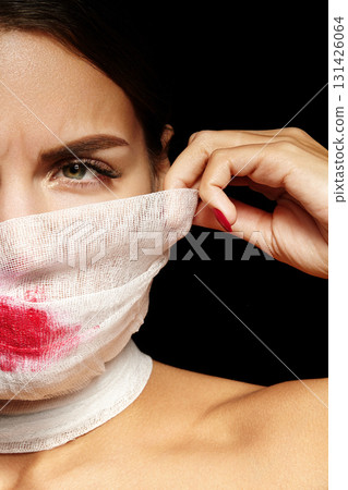 Portrait of woman in bandage mask with red lipstick. Conceptual artistic look for Halloween makeup, Mummy style, plastic surgery clinic Portrait of woman in bandage mask with red lipstick. Conceptual artistic look for Halloween makeup, Mummy style, plastic surgery clinic 131426064