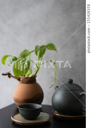 Asian tea set and mini philodendron in a brown earthenware pot with dark grey grunge wall background 131426358