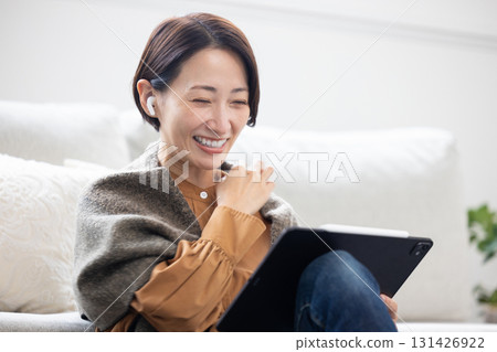 一位中年女性正在使用無線耳機的平板電腦 131426922
