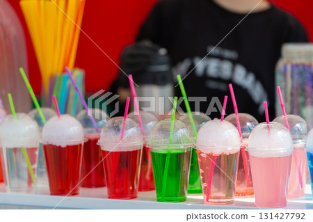 Colorful carbonated drinks in plastic cups with a straw close-up. Colorful carbonated drinks in plastic cups with a straw close-up. 131427792