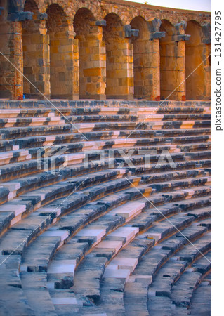 Part of the amphitheater with a stone staircase and a wall in the background. The wall has arches 131427795