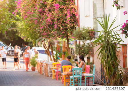 A blurred, blooming street of a tropical resort town with palm trees and a cozy, colorful cafe. 131427807