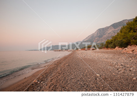 Calm morning landscape of pebble sand beach sea and mountains. 131427879