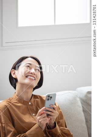 一位中年婦女拿著智慧型手機微笑 131428701