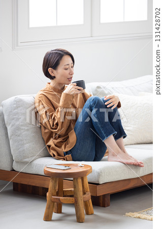 Middle-aged woman drinking coffee on the sofa 131428702