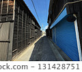 An old alleyway surrounded by black walls and blue shutters 131428751