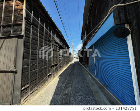 An old alleyway surrounded by black walls and blue shutters An old alleyway surrounded by black walls and blue shutters 131428751