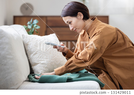 一名女子用智慧型手機拍攝衣服照片 131429011
