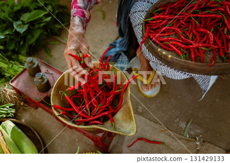 In a bustling market, vibrant red chili peppers add a colorful touch to the scene 131429133