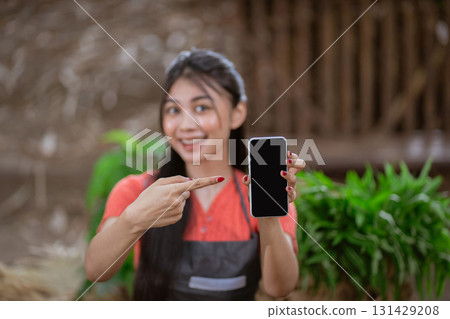 A Cheerful Woman Proudly Showing Her Smartphone in a Beautiful Natural Outdoor Setting 131429208