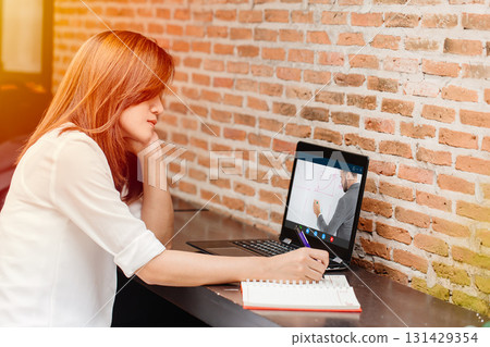 e-learning concept, woman watching teacher live internet video streaming lecture from laptop computer screen at cafe. 131429354