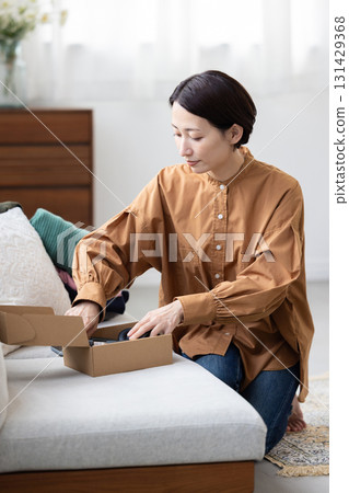 Woman packing headphones into a box 131429368