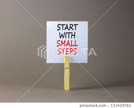 Start with small steps symbol. Concept words phrase Start with small steps on beautiful white paper on clothespin. Beautiful grey background. Business Start with small steps concept. Copy space. 131429783