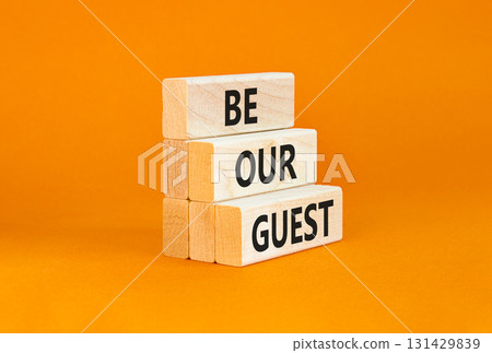 Be our guest symbol. Concept words Be our guest on beautiful wooden block. Beautiful orange table orange background. Business and be our guest concept. Copy space. 131429839