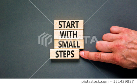 Start with small steps symbol. Concept words phrase Start with small steps on beautiful wooden blocks. Beautiful grey background. Businessman hand. Business Start with small steps concept. Copy space. 131429857