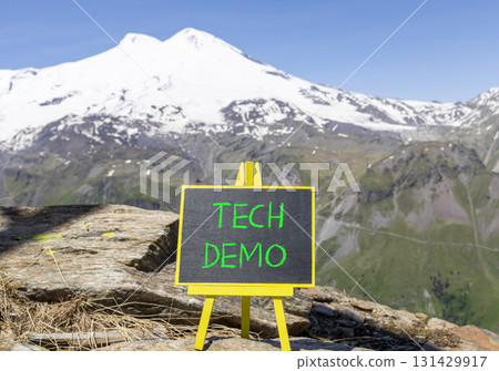 Tech demo symbol. Concept word Tech demo on beautiful black blackboard. Beautiful stone mountain Elbrus blue sky background. Black blackboard. Business tech demo concept. Copy space. 131429917