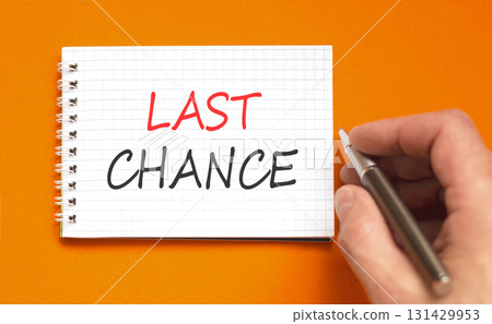 Last chance symbol. Concept word Last chance on beautiful white note. Businessman's hand with pen. Beautiful orange paper background. Business last chance concept. Copy space. Last chance symbol. Concept word Last chance on beautiful white note. Businessman's hand with pen. Beautiful orange paper background. Business last chance concept. Copy space. 131429953