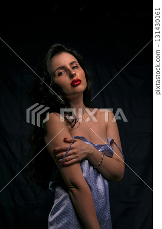 woman stands elegantly with her arms crossed wearing a light blue outfit. Her dark hair cascades around her shoulders and she gazes confidently at the camera in a studio setting. woman stands elegantly with her arms crossed wearing a light blue outfit. Her dark hair cascades around her shoulders and she gazes confidently at the camera in a studio setting. 131430161