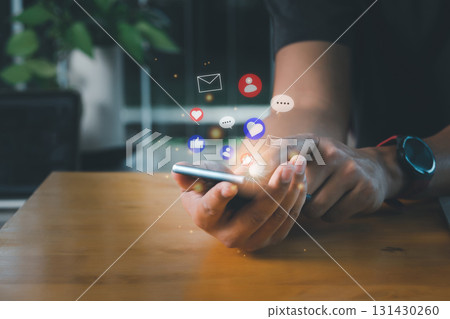 Social media and digital online concept. A man using smart phone for social media with notification icons of contact, love, like, message, and email. Working from home and social distancing concept. Social media and digital online concept. A man using smart phone for social media with notification icons of contact, love, like, message, and email. Working from home and social distancing concept. 131430260