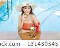 Sexy young asian woman in swimsuits in summer. beautiful woman in orange bikini with hat and tropical drink in swimming pool. 131430345