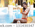 Sexy young asian woman in swimsuits in summer. beautiful woman in orange bikini with sunglasses and tropical drink sitting in swimming pool. 131430347
