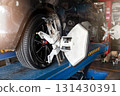 Car wheel balancer calibrate with laser reflector attach on each tire to center driving adjust. Car in auto service. Balancing tire wheel machine. 131430391