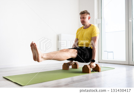 Sporty Man Doing Sport Exercises With Floor Dip Bars, Doing Core Strength With An L-Sit On Parallettes 131430417