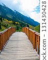 A wooden bridge with a brown color and a simple design is constructed across a flowing river. The bridge is positioned in the center of the image, with the river flowing underneath it. 131430428
