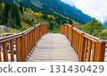 A wooden bridge with a brown color and a simple design is constructed across a flowing river. The bridge is positioned in the center of the image, with the river flowing underneath it. 131430429