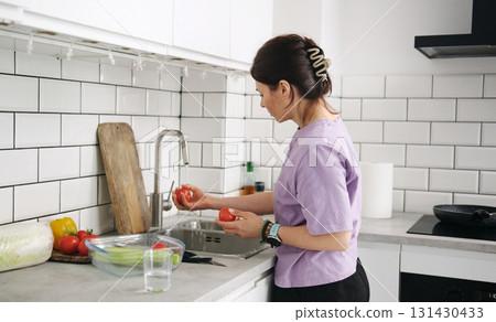 Girl Washing Tomatoes And Vegetables In The Kitchen For Preparing Salad 131430433