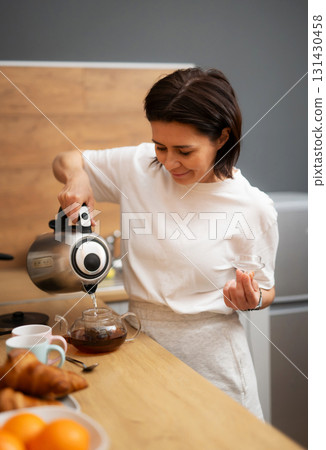 Girl Pouring Boiling Water Into Teapot With Black Tea In The Kitchen For Breakfast 131430458