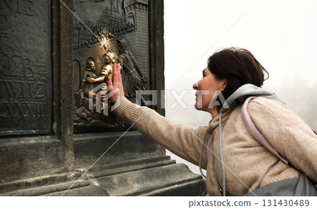 Tourist Girl On Charles Bridge Touching Bronze Bas-Relief For Good Luck 131430489