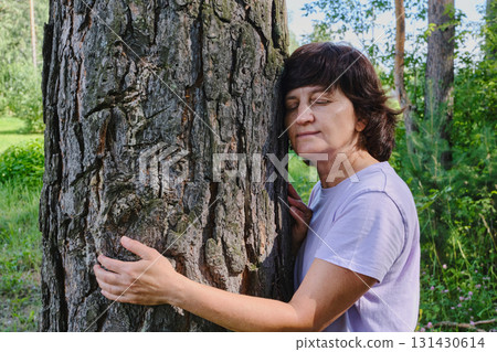 Mature caucasian woman embracing tree in peaceful forest setting 131430614