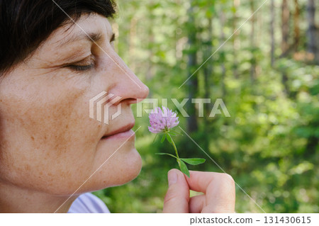 Mature caucasian female enjoying nature with wildflower in forest 131430615