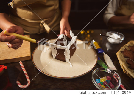 Family Decorating Chocolate Cake With White Icing For Christmas Celebration At Home 131430949