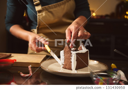 Home Chef Icing A Gingerbread House During Christmas Baking In A Cozy Kitchen 131430950