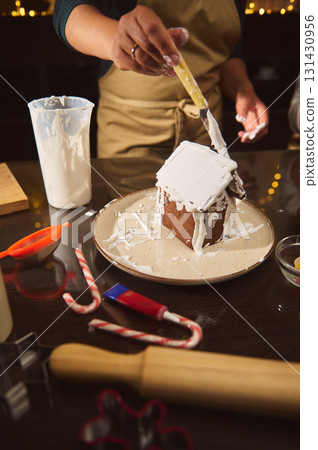 Baker Icing A Gingerbread House During Christmas Decorating Session 131430956