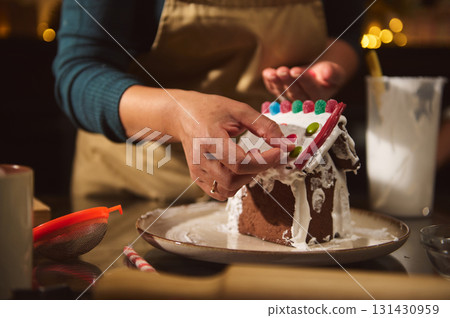 Gingerbread House Decorating With Icing And Candies In Cozy Home Kitchen Gingerbread House Decorating With Icing And Candies In Cozy Home Kitchen 131430959